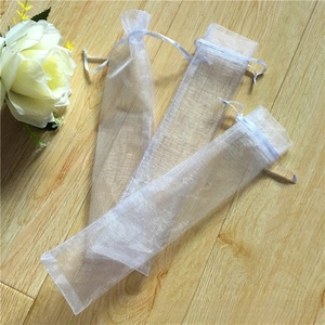 White organza drawstring pouches for pens and jewelry packaging on wood background