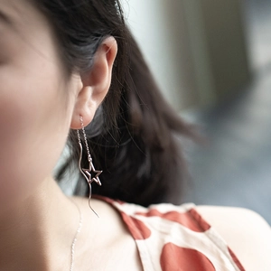Close-up of rose gold star-shaped threader earring worn by a model with soft lighting