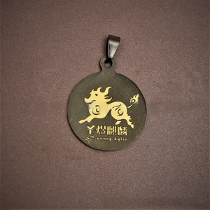 Detail of round bronze titanium steel dog tag with golden Kylin motif and brushed finish