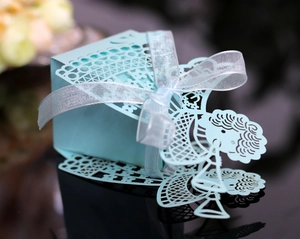 Detail of light blue laser-cut gift box with angel design and silver glitter ribbon bow