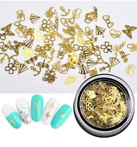 Détail de breloques à ongles en métal doré de formes variées présentées en boîte ronde