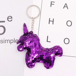 Close-up of a purple sequin unicorn keychain with metal ring on a decorative card