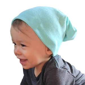 Close-up of a soft mint green cotton knit beanie cap on a baby with ribbed edge