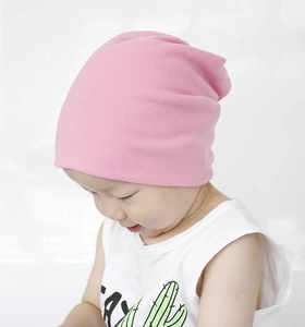 Detail showing the soft pink cotton baby beanie worn by a child in a minimalist setting
