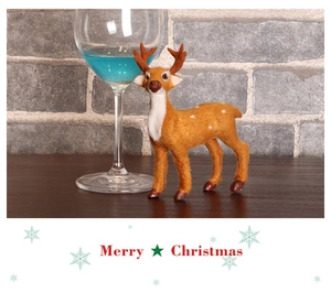 Close-up of realistic plush Christmas reindeer figurine with white spots on wooden desk
