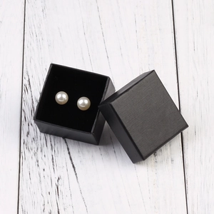 Elegant white pearl earrings in a premium black gift box on a white wooden background