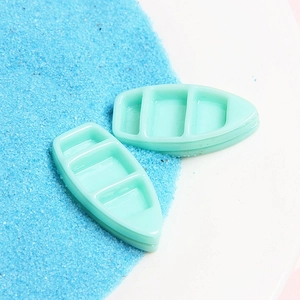 Macro view of light green toy boats on blue sand background for marine DIY crafts
