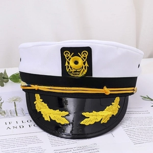 Detail of nautical captain hat with gold embroidery and braided rope on magazine background