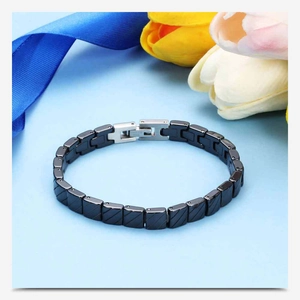 Detail of black ceramic chain link bracelet with silver clasp on a blue floral background