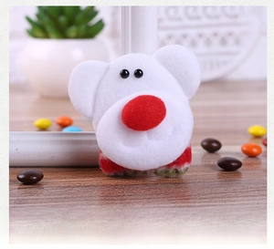 Detail of Christmas plush brooch with red nose on wooden surface with festive props