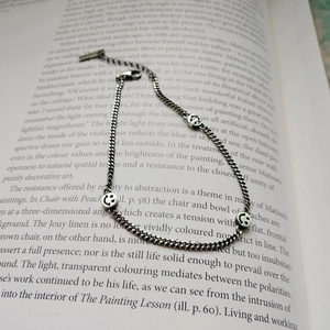 Macro shot of silver chain anklet with smiley charms on open book pages