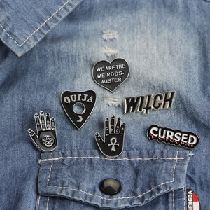Gothic metal enamel pin set with heart, ouija and witch designs on denim jacket