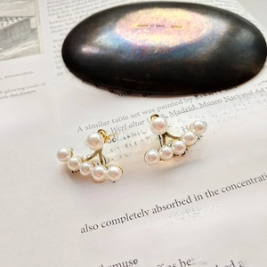 Detailed macro view of gold fan-shaped pearl earrings on a vintage art book