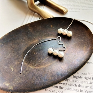 Detailed view of sterling silver threader earrings with three elegant white pearls