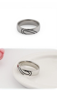 Polished silver titanium steel heart ring shown on a white plate with pink petals