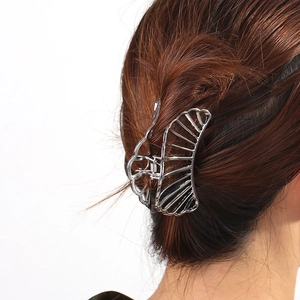Detail of a large silver hollow butterfly hair claw clip styled on brown hair