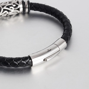 Macro detail of men's black braided leather bracelet with vintage engraved silver clasp