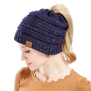 Detail of navy knit ponytail beanie with multicolored flecks and brown leather C.C tag