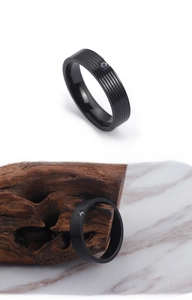 Detailed macro view of black titanium ring featuring a single stone inlay and grooved texture