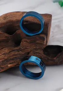 Detail view of a wide blue titanium steel ring with male gender symbols on wood