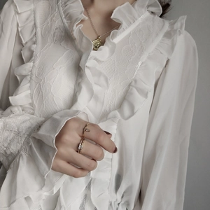 Close-up of gold-plated 925 silver rings and coin pendant on a lace blouse background