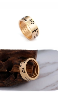 Close-up of gold titanium steel ring with black artistic symbols on a wooden stand