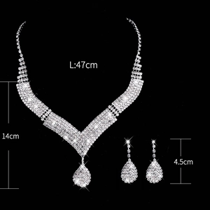 Silver bridal jewelry set featuring diamond-encrusted necklace and earrings on black background