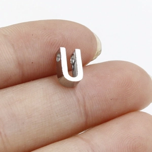 Close-up of a small silver polished stainless steel U-shaped DIY connector held by fingers