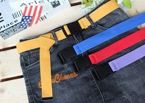 Detail of colorful canvas belts with plastic buckles styled on a black denim skirt