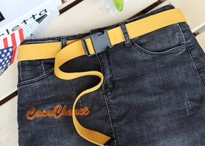 Close-up of yellow canvas tactical belt with a black plastic buckle on denim pants