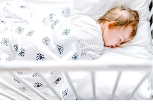 Bébé endormi dans une couverture d'emmaillotage en mousseline blanche à motifs de flocons