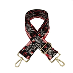 Detail of adjustable woven bag strap with red and white geometric patterns and gold clips