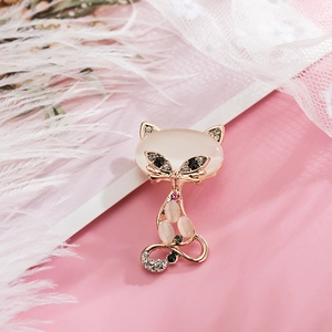 Elegant gold metal cat brooch with white opal stones and rhinestones on pink background