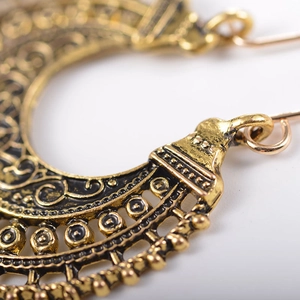 Macro detail of antique gold bohemian hollow engraved semi-circle hoop earrings