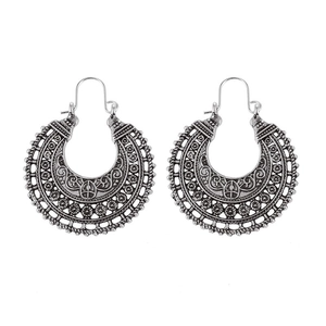 Detail of silver bohemian hoop earrings with intricate hollow carved floral texture