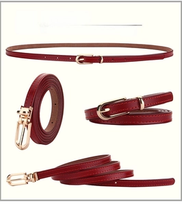 Detail view of red slim leather belt for women with gold oval pin buckle and stitching