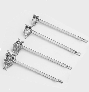 Close-up of four vintage silver owl hairpins with rhinestone eyes on white background