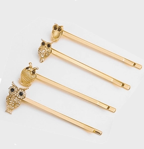 Detail view of four gold-tone owl hairpins with sparkling rhinestones on white background
