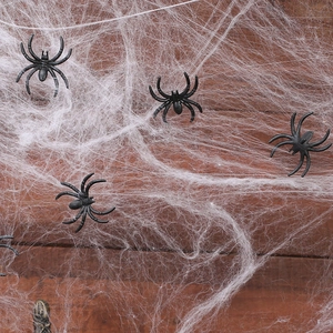 Detail of realistic black plastic spiders on white fiber web over brown wood background
