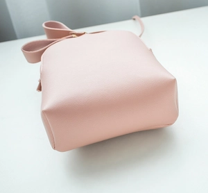 Detail of pink faux leather mini crossbody bag showing lychee grain texture and stitching