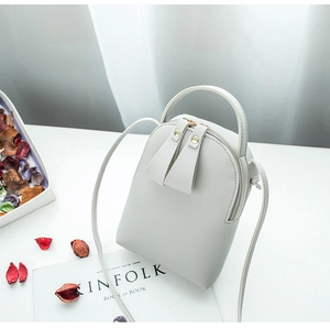 Minimalist mini leather crossbody bag in light grey on a clean white countertop