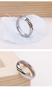 Detailed view of silver and gold heart-shaped matching couple rings with metal texture