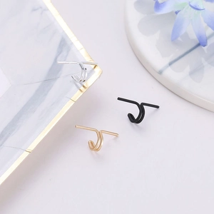 Three minimalist metal U-shaped ear cuffs in silver, black and gold on marble display