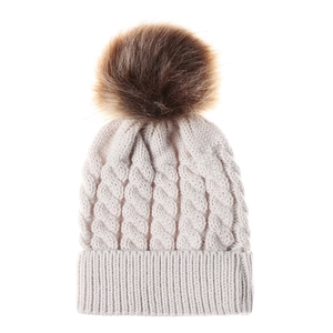 Detailed view of cream cable knit beanie with fluffy faux fur pompom and soft texture