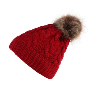 Close-up of burgundy cable knit winter hat with a fluffy brown faux fur pom pom