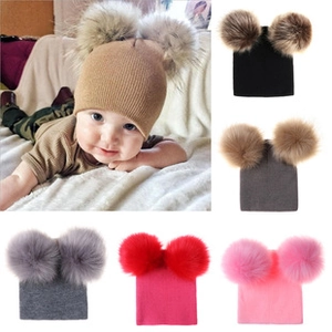 Detail showing various colors of knitted baby hats with double faux fur pom poms