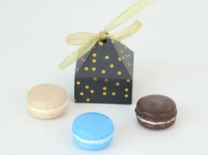 Macro shot of black pyramid gift box with gold dots and matching gold mesh ribbon