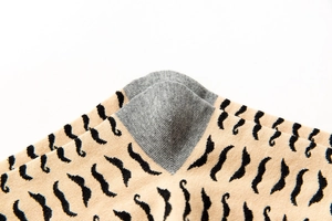 Detailed close-up of grey heel on beige cotton socks with black mustache patterns
