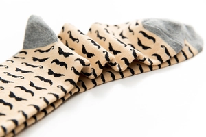 Detail of knitted cotton socks with black mustache pattern and grey heel patches