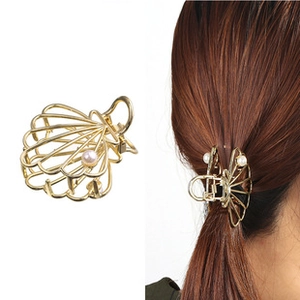 Détail d'une pince à cheveux coquillage dorée avec perle et coiffure sur modèle